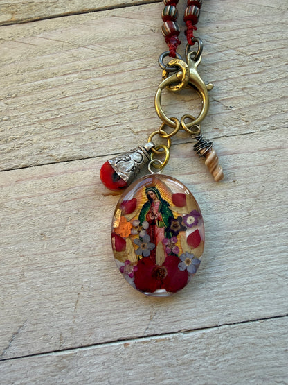 Our Lady. Dried flowers under resin. Handmade with sterling bezel on knotted striped Java beads. 35” necklace.