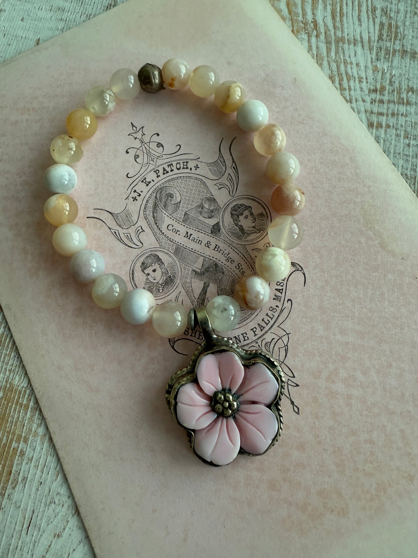 Tibetan carved Peruvian Opal charm on cherry blossom agate beads stretch bracelet. 6.5”