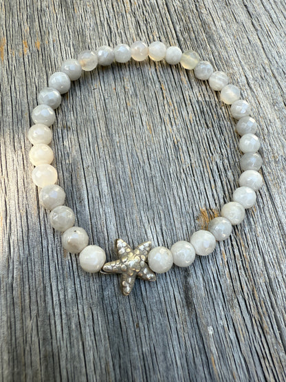 A small, fine silver starfish adorns this faceted moonstone bracelet. 7-7.5” stretch.