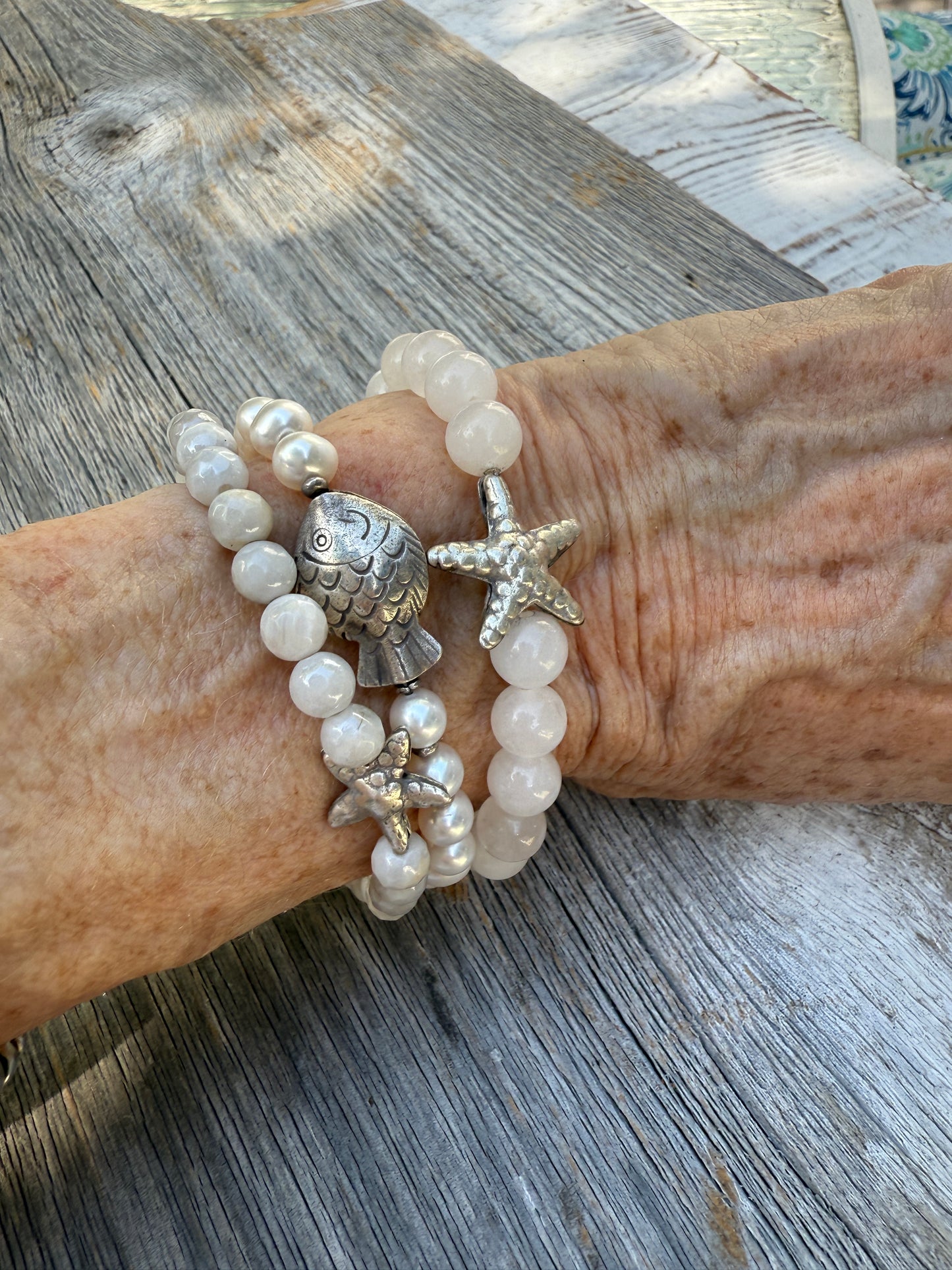 A small, fine silver starfish adorns this faceted moonstone bracelet. 7-7.5” stretch.