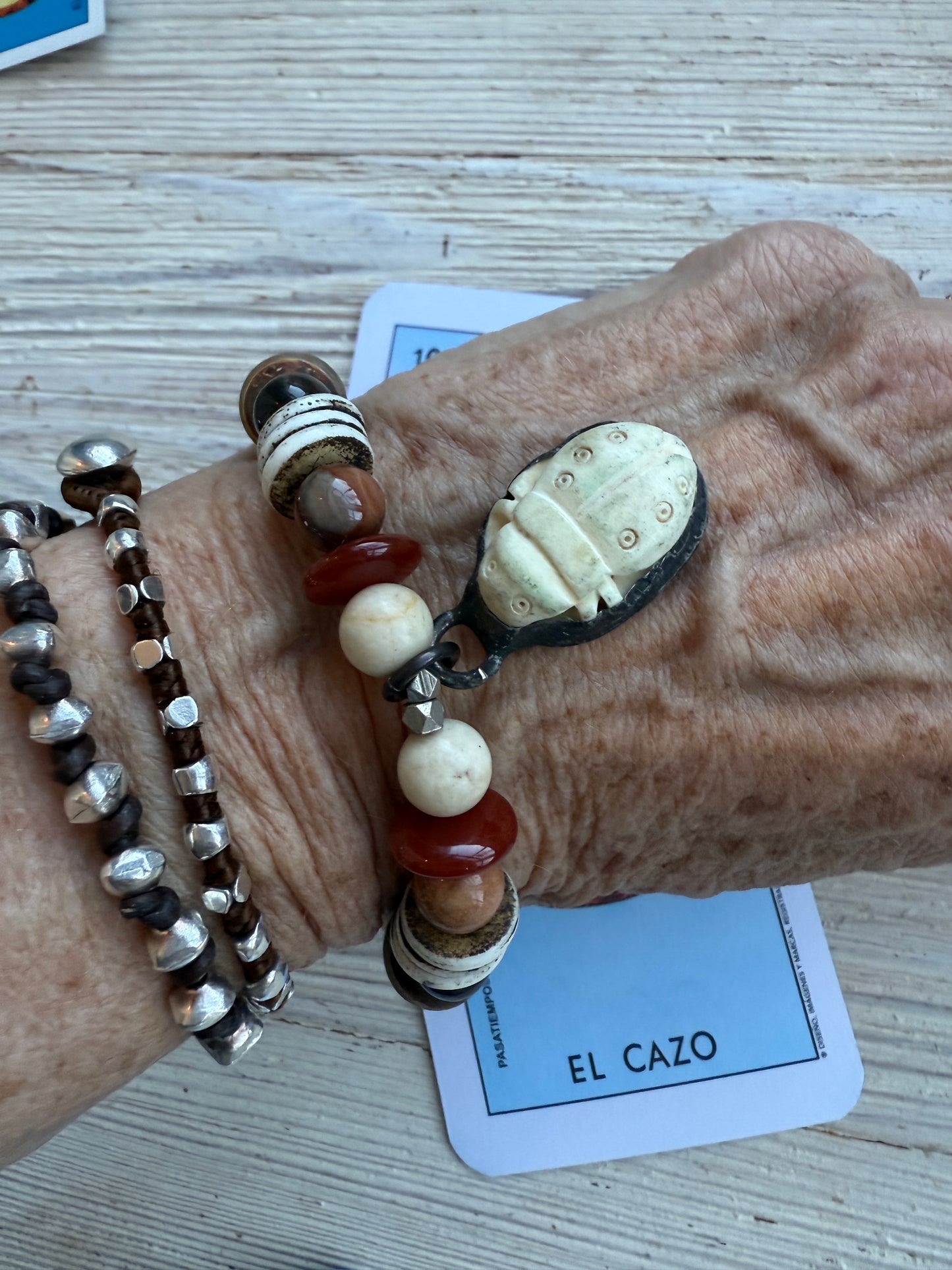 A bone scarab dangles from a mix of earthy beads stretch bracelet 6.5-7”