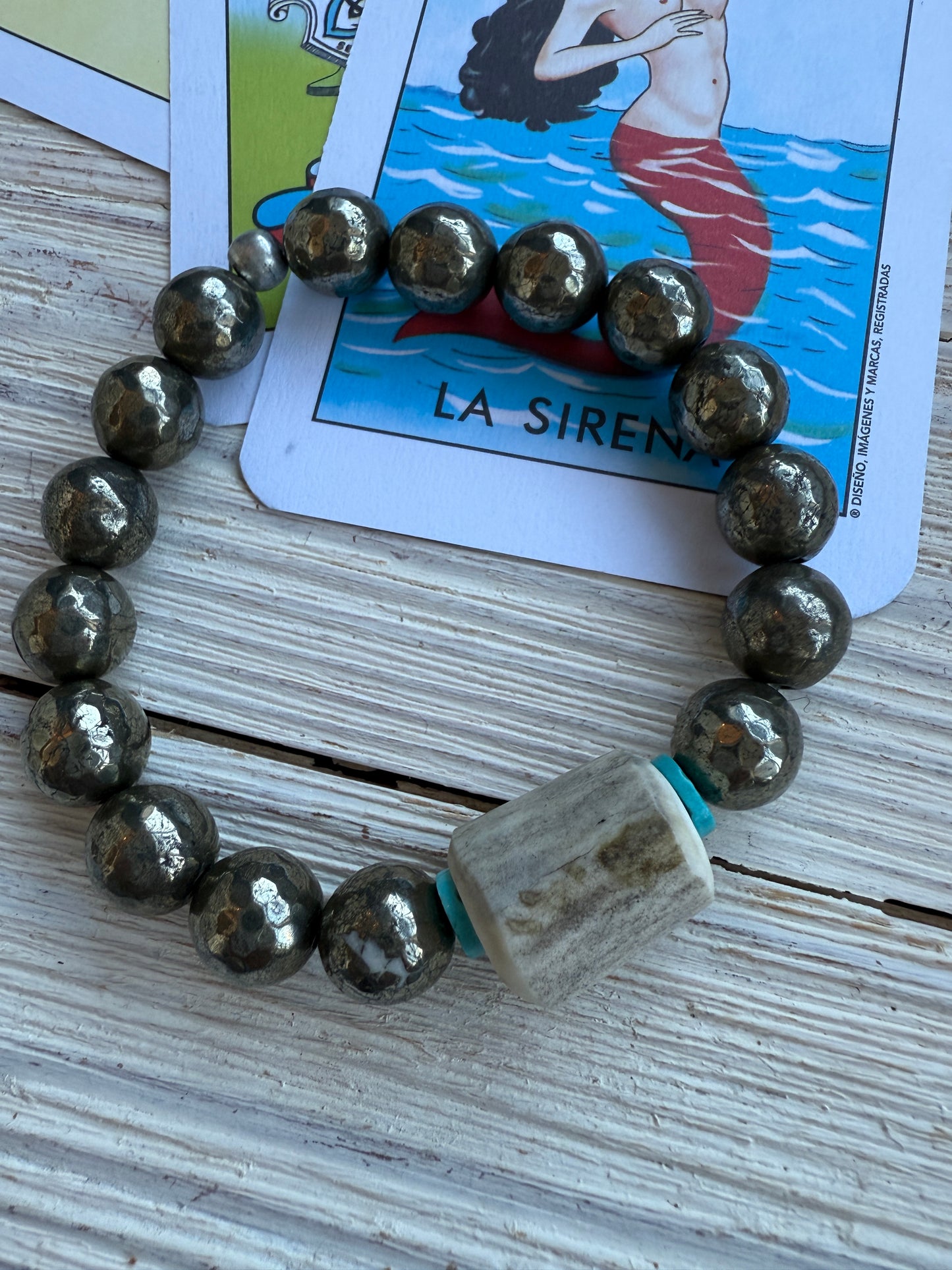 Pyrite beads surround an antler with turquoise accents stretch bracelet. 6.5”