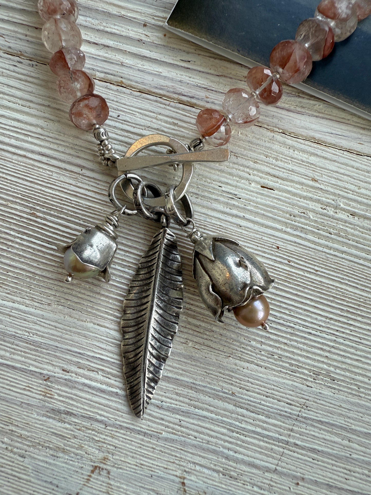 Hematoid quartz with fine silver spacers with fine silver rosebud, rose, and leaf on a fine silver front toggle necklace. 18”