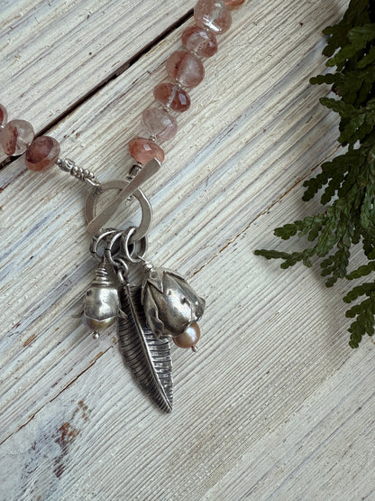 Hematoid quartz with fine silver spacers with fine silver rosebud, rose, and leaf on a fine silver front toggle necklace. 18”