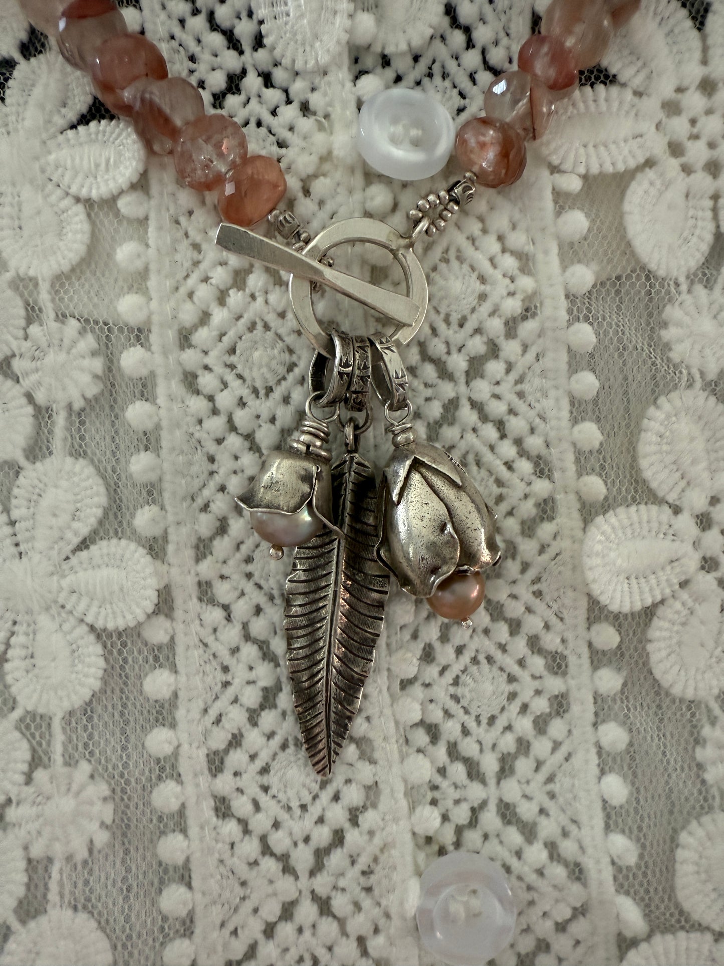 Hematoid quartz with fine silver spacers with fine silver rosebud, rose, and leaf on a fine silver front toggle necklace. 18”