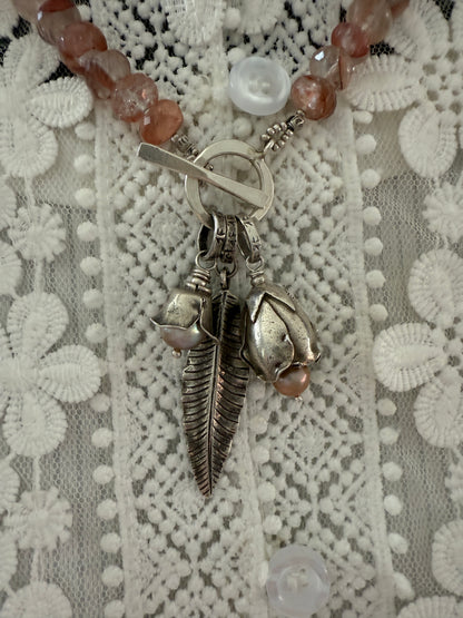 Hematoid quartz with fine silver spacers with fine silver rosebud, rose, and leaf on a fine silver front toggle necklace. 18”