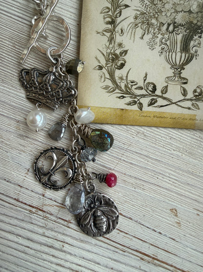 Sterling silver crown, fleur de lis, and bee charms on long fine silver chain. 25.5”