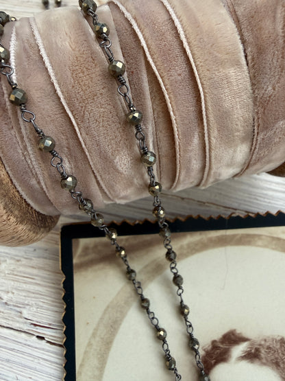 Antiqued bronze glass locket on pyrite chain. 32”