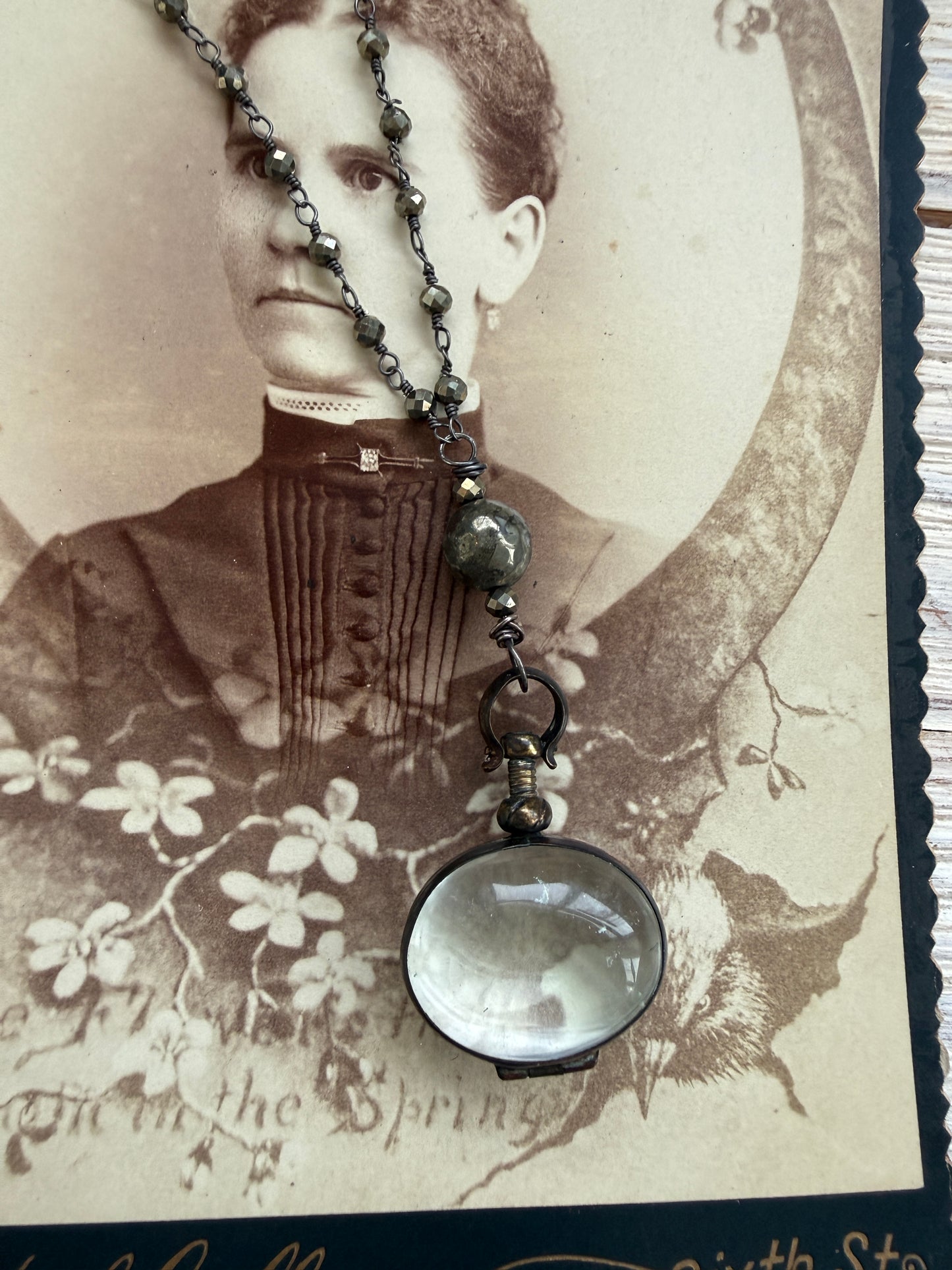 Antiqued bronze glass locket on pyrite chain. 32”