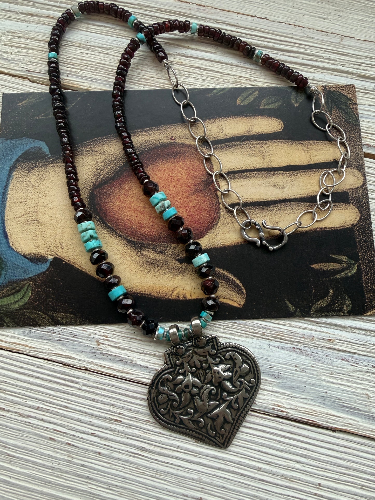 A hand-cast white bronze pendant with garnets, turquoise, and fine silver necklace.