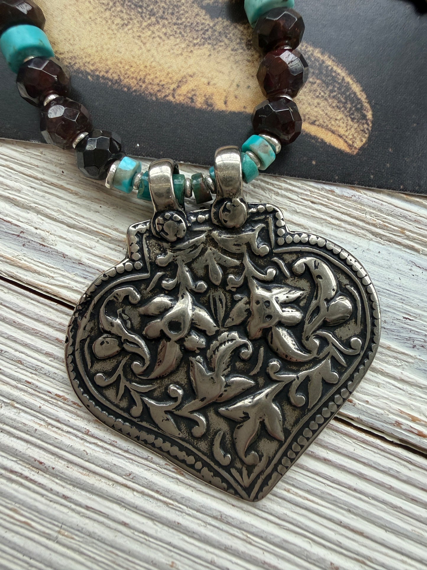 A hand-cast white bronze pendant with garnets, turquoise, and fine silver necklace.