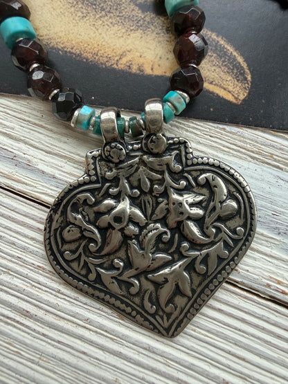 A hand-cast white bronze pendant with garnets, turquoise, and fine silver necklace.
