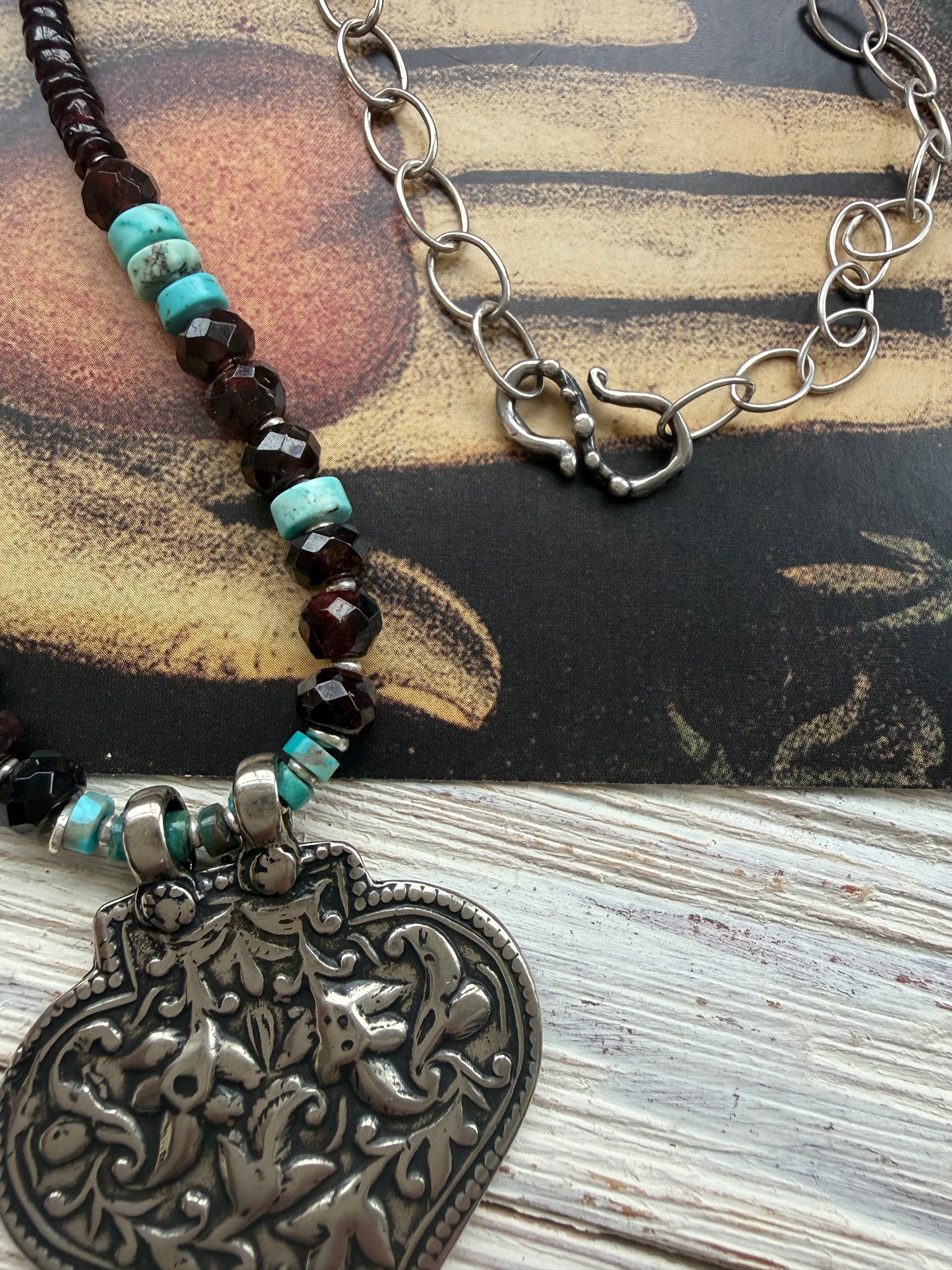 A hand-cast white bronze pendant with garnets, turquoise, and fine silver necklace.