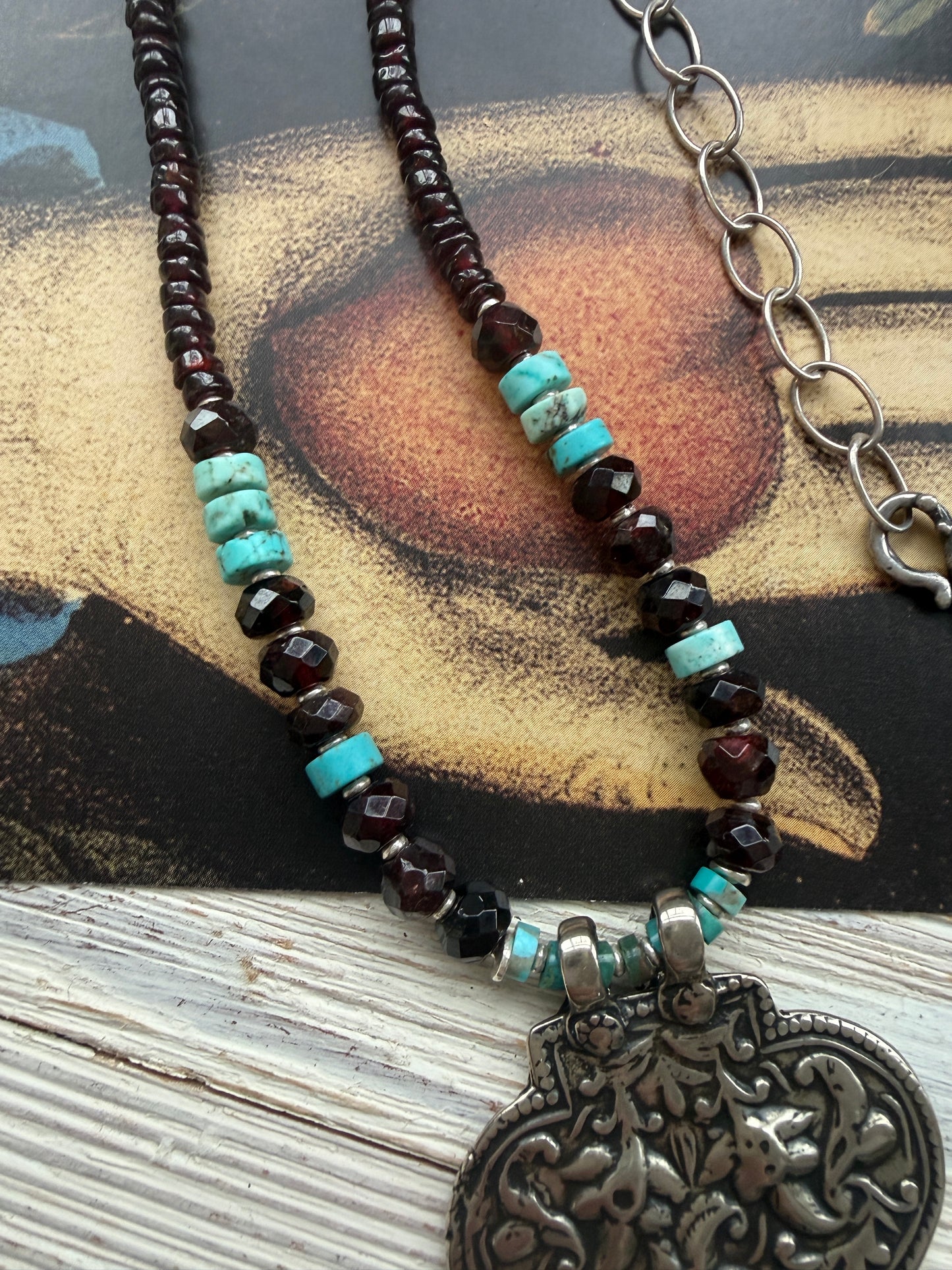 A hand-cast white bronze pendant with garnets, turquoise, and fine silver necklace.