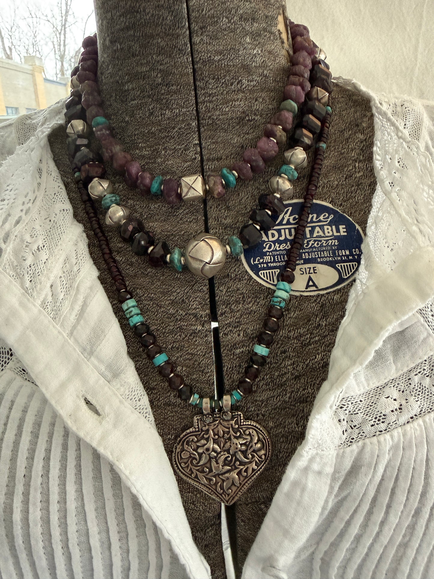 A hand-cast white bronze pendant with garnets, turquoise, and fine silver necklace.