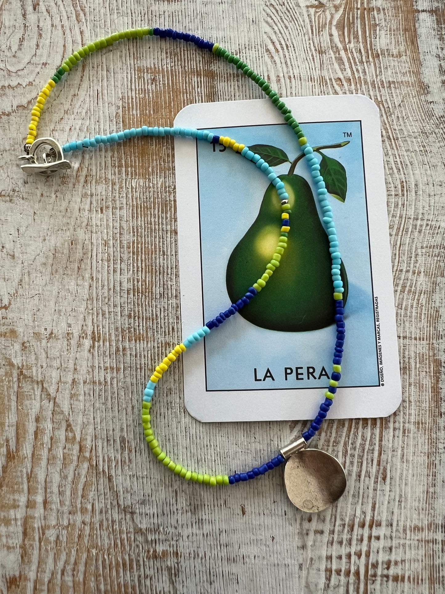 Blue, turquoise, green, and yellow glass beads from Java with a full moon pendant of fine silver.