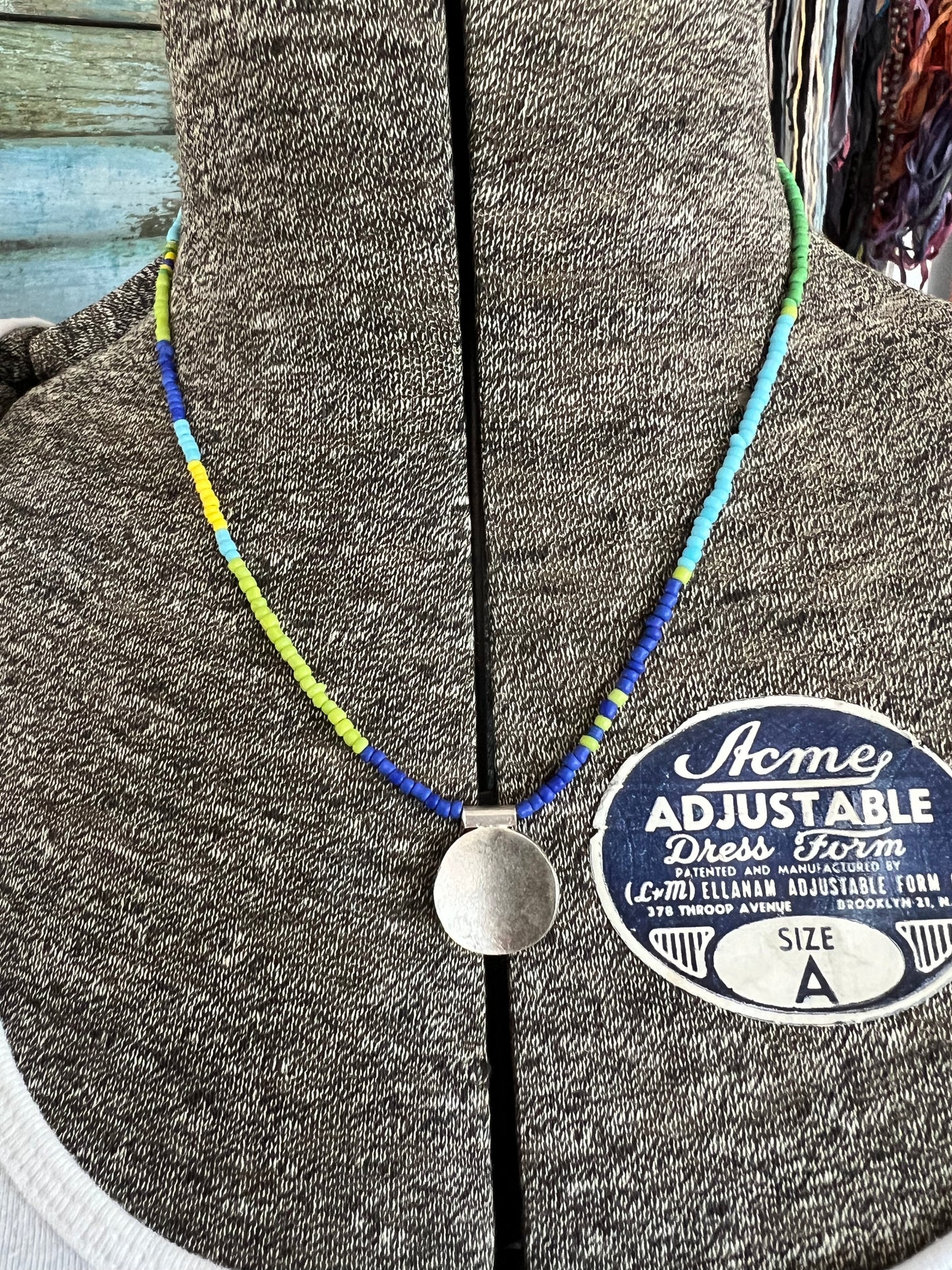 Blue, turquoise, green, and yellow glass beads from Java with a full moon pendant of fine silver.