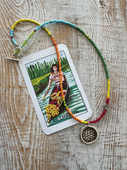 Primary colors surround a woven fine silver pendant necklace.