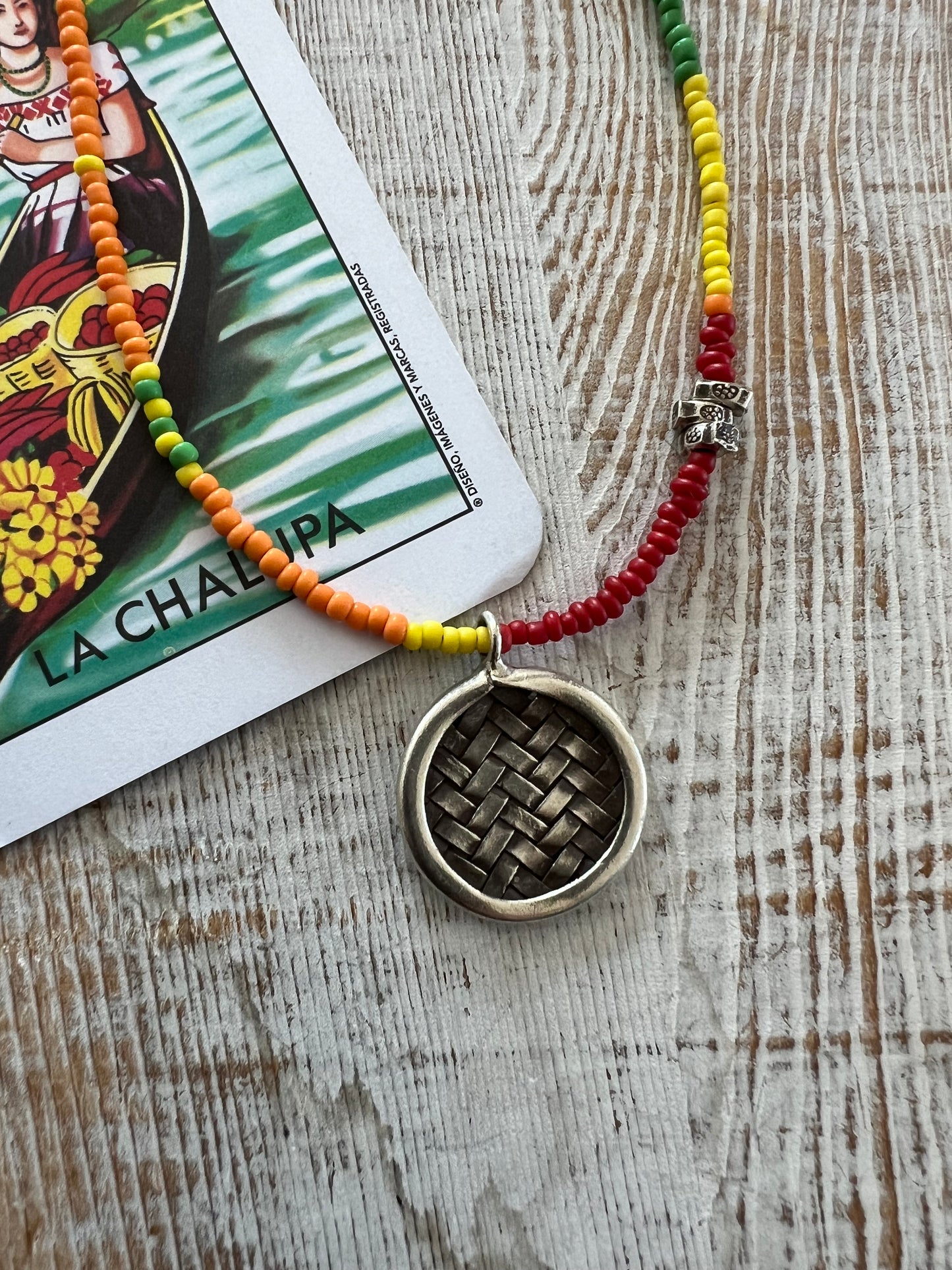 Primary colors surround a woven fine silver pendant necklace.