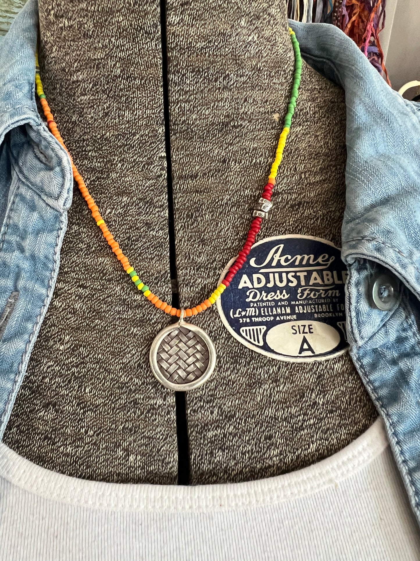 Primary colors surround a woven fine silver pendant necklace.