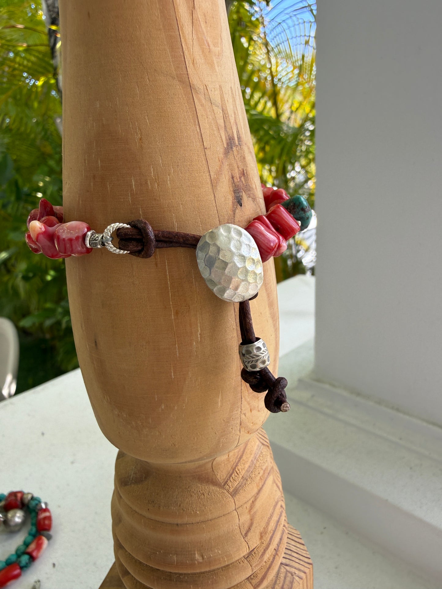 Coral beads connected by a fine silver hammered button and leather loop. 6.5”