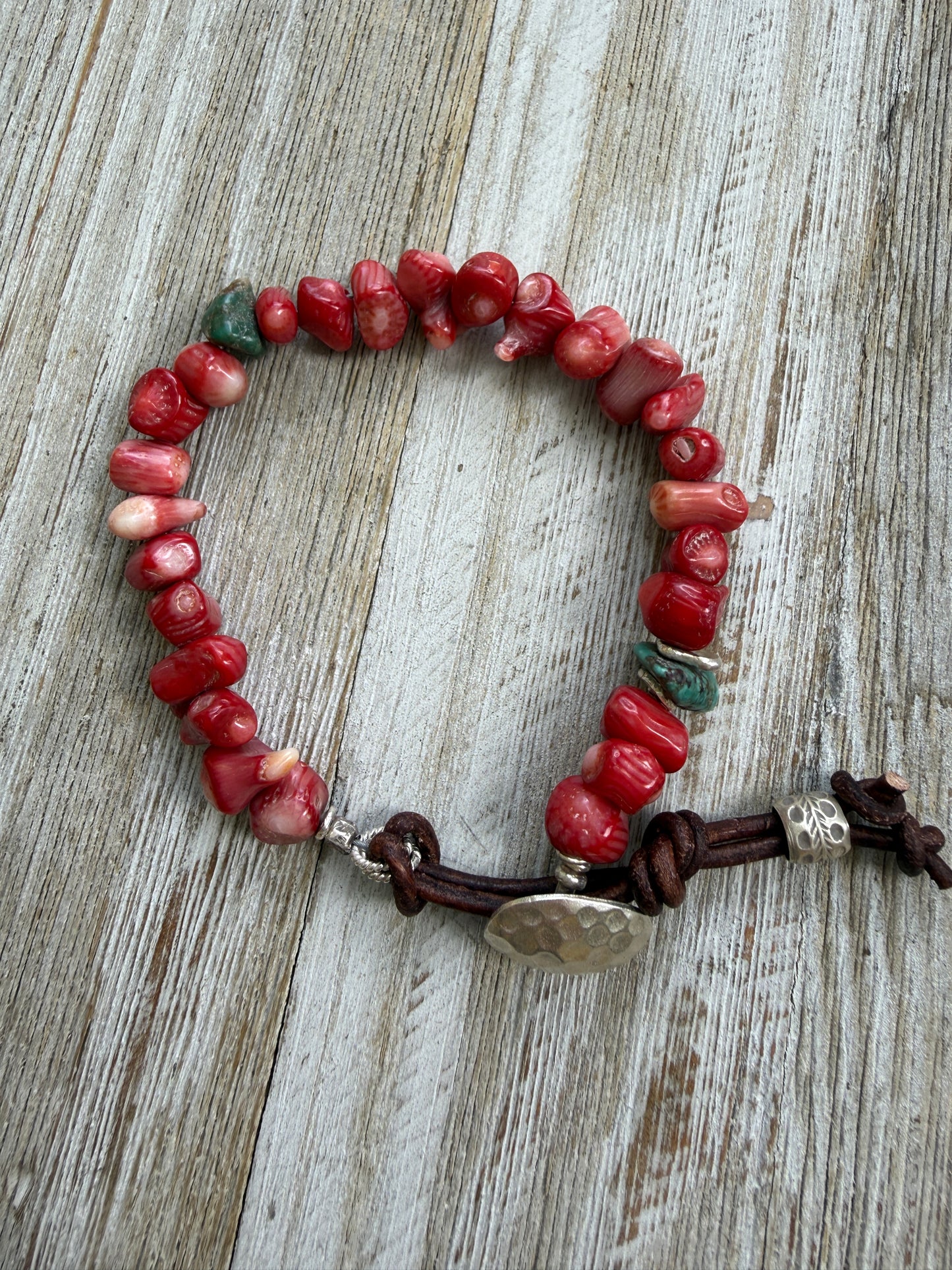 Coral beads connected by a fine silver hammered button and leather loop. 6.5”