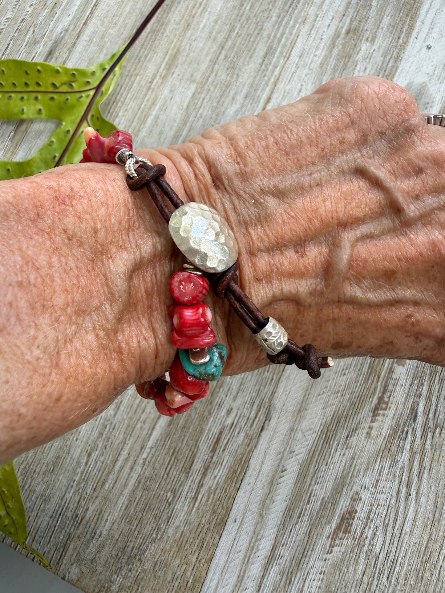 Coral beads connected by a fine silver hammered button and leather loop. 6.5”