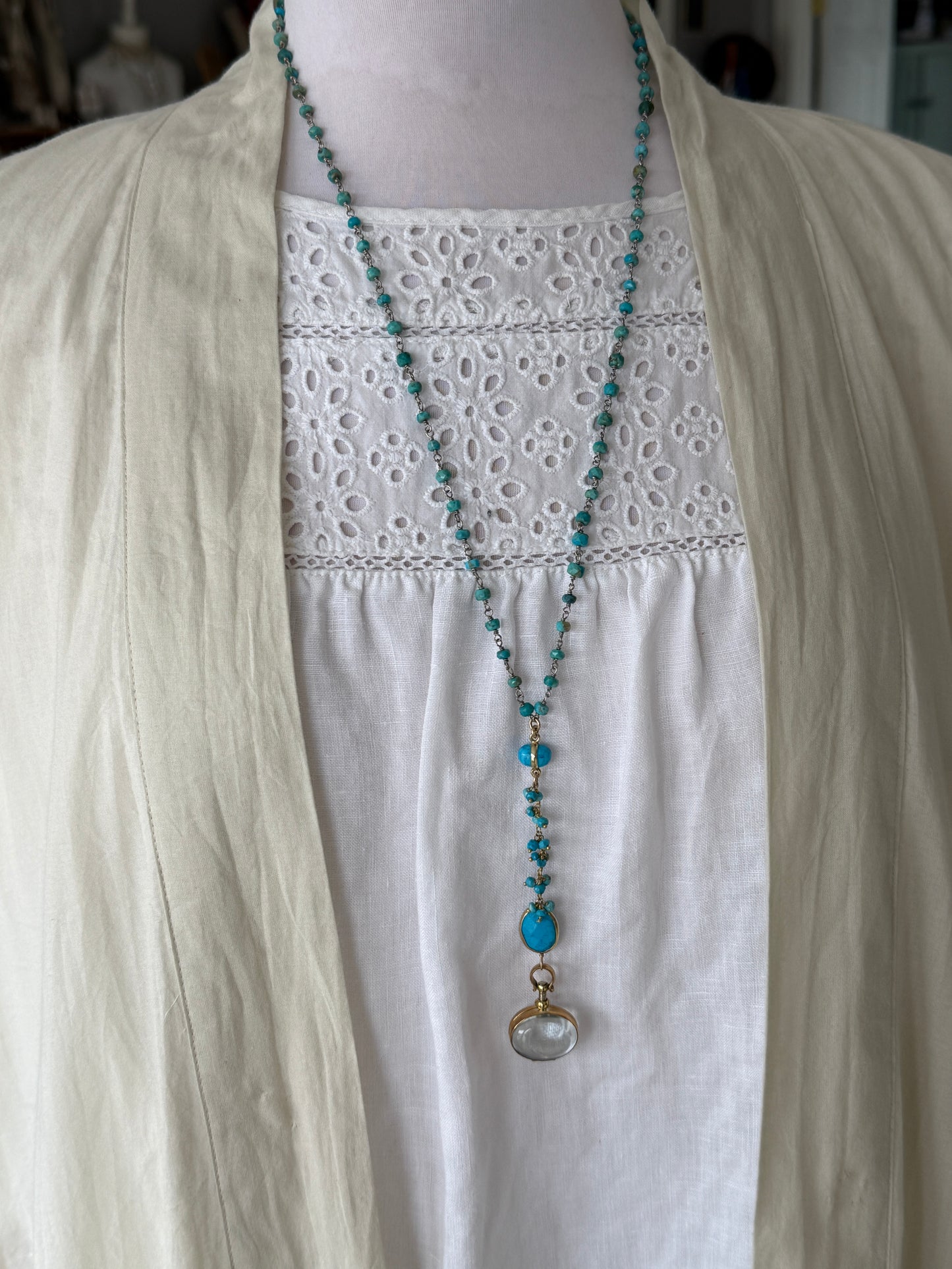 Turquoise rosary style chain with turquoise and gold accent pieces and brass locket necklace.