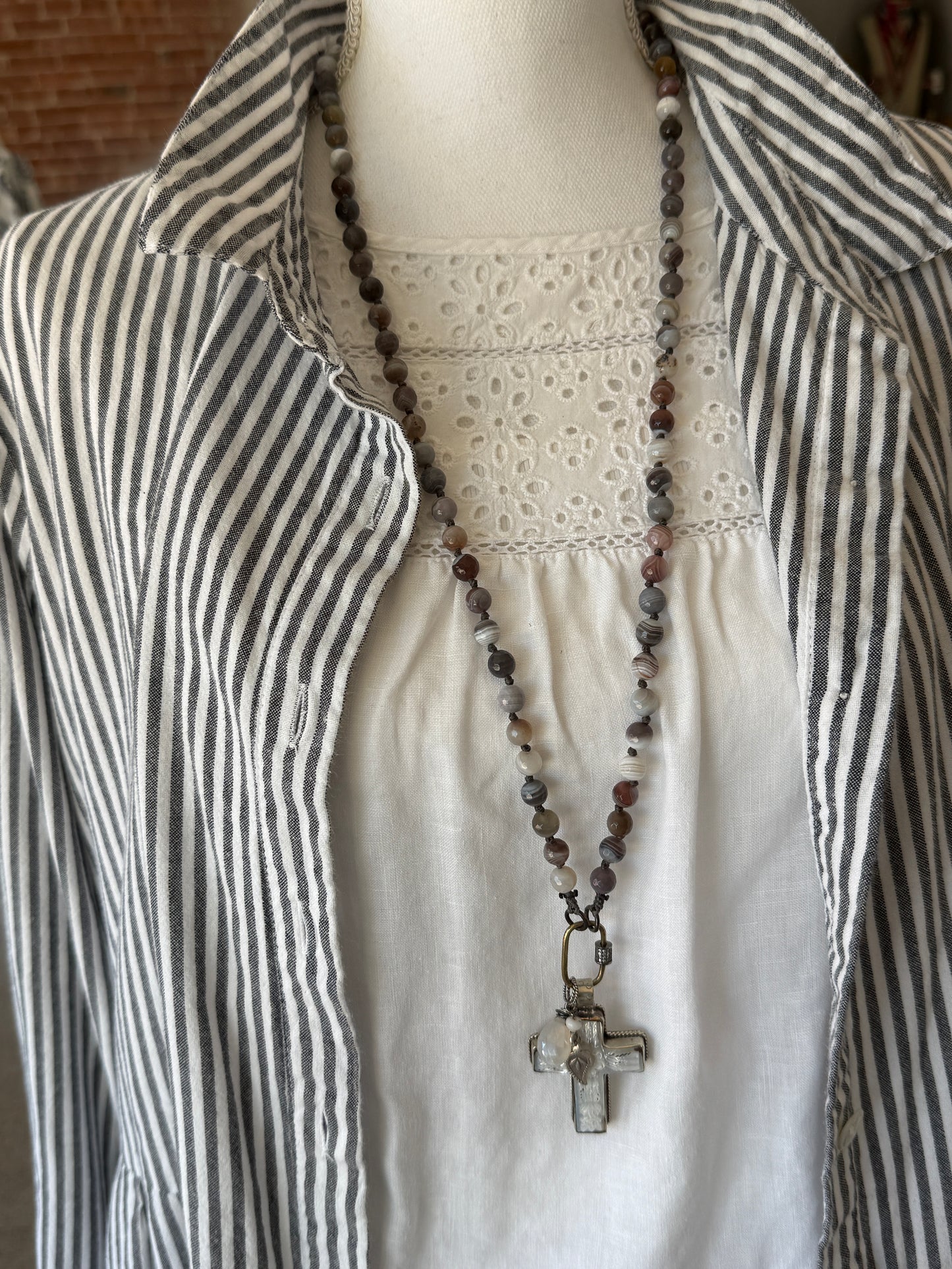 Carved Tibetan Mother of Pearl cross on knotted, faceted Botswana agates necklace.