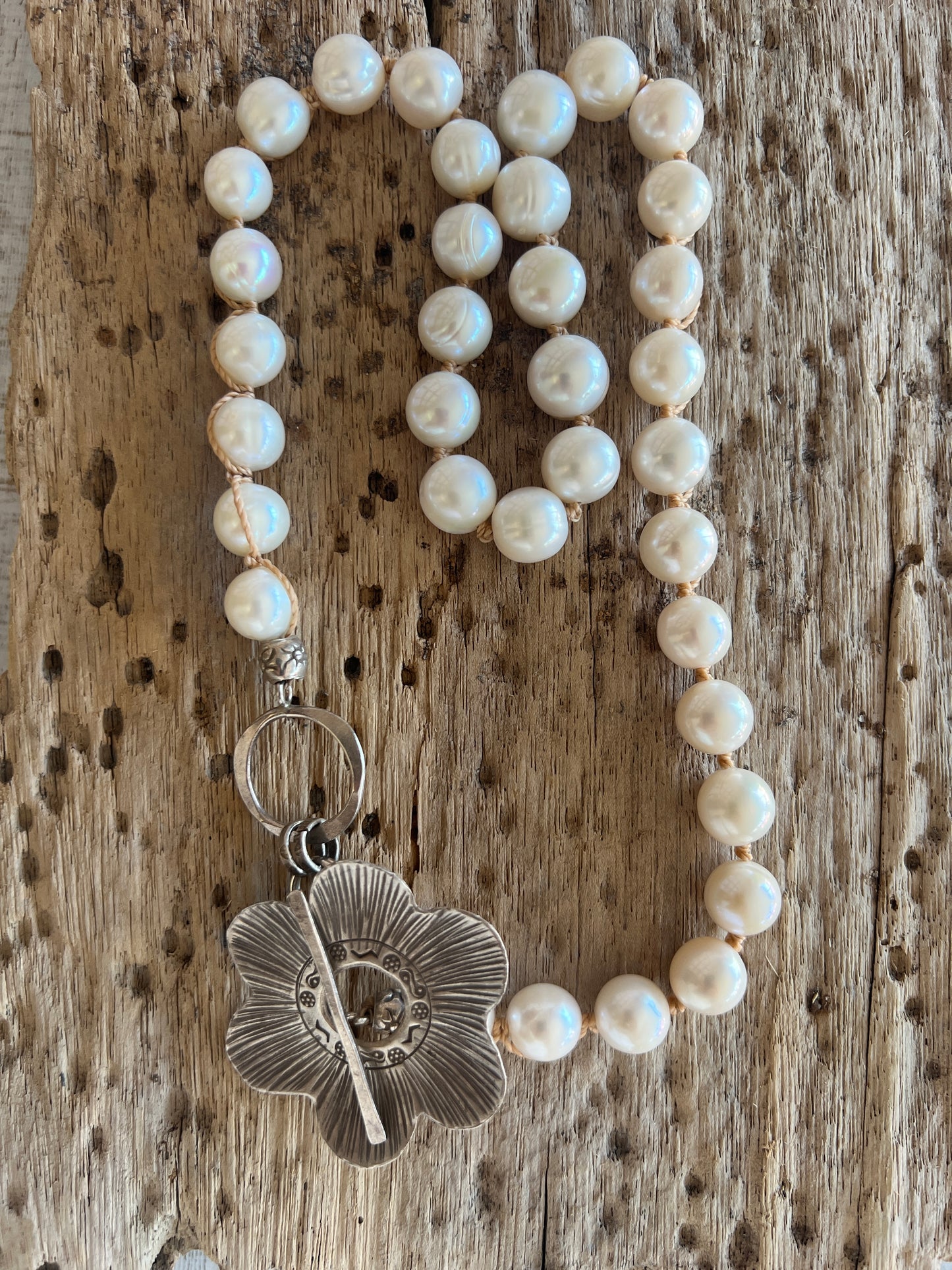 Fine silver flower on hand knotted pearls necklace. Front or side toggle