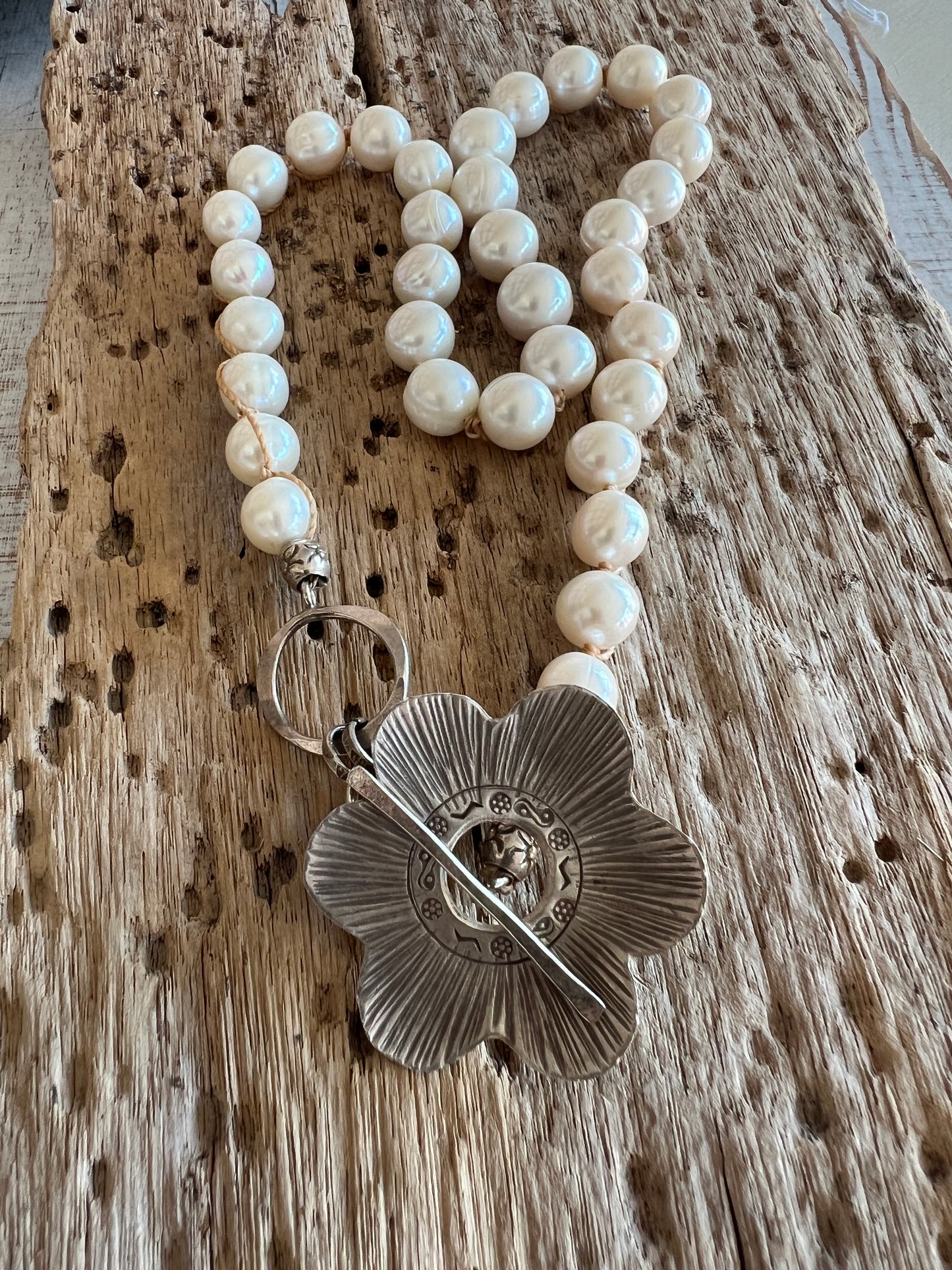 Fine silver flower on hand knotted pearls necklace. Front or side toggle