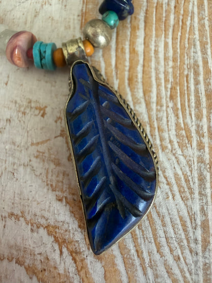 Carved lapis lazuli leaf from Tibet on a mix of gems and trade beads necklace. 25”.