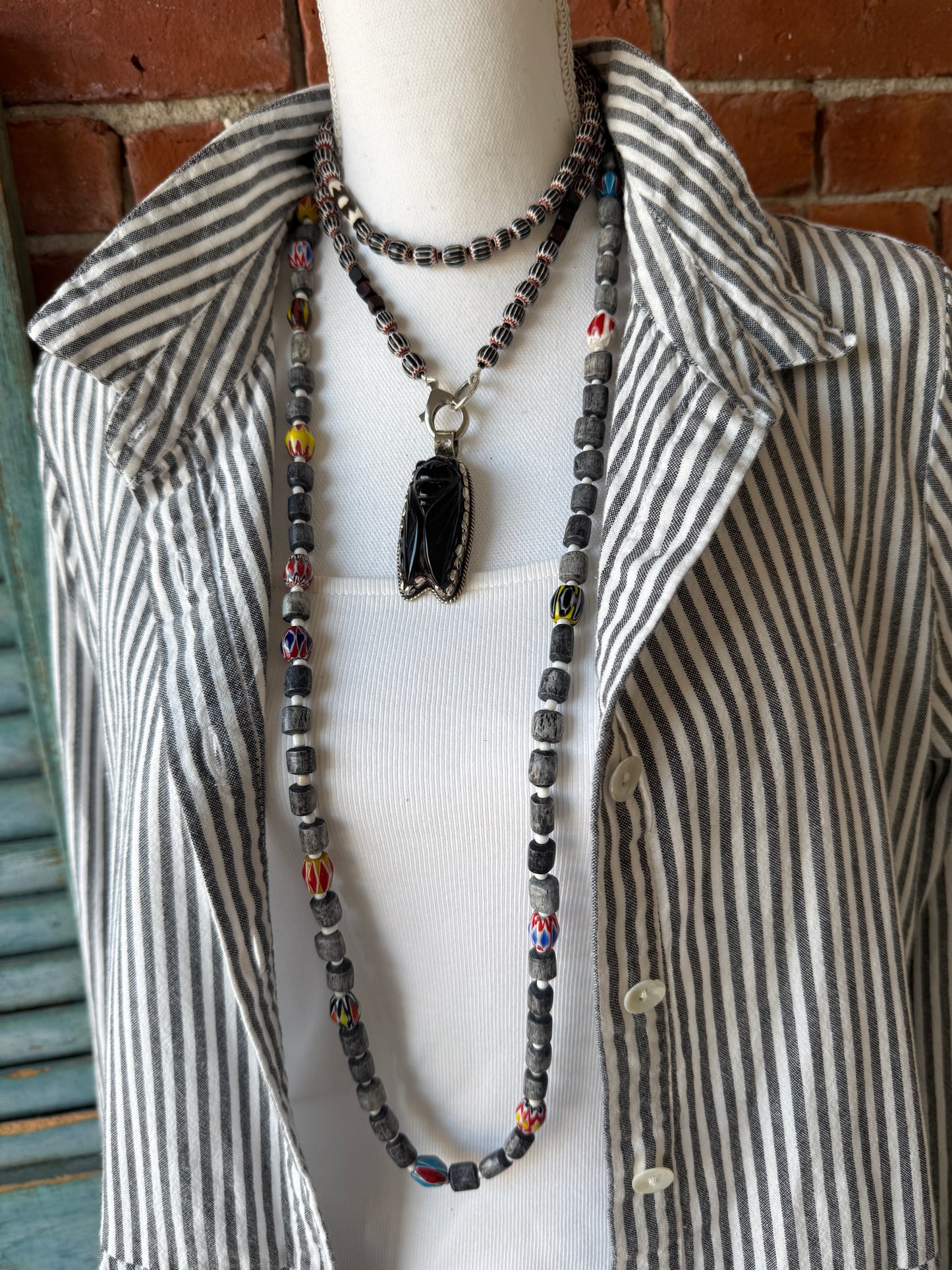 Obsidian beetle pendant on black, red, and white chevron beads with bone accent beads long necklace. Front lobster clasp. 34”