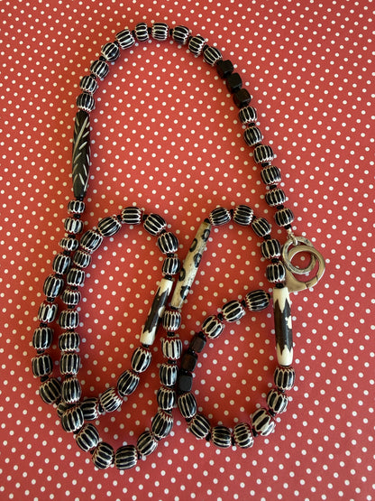Obsidian beetle pendant on black, red, and white chevron beads with bone accent beads long necklace. Front lobster clasp. 34”
