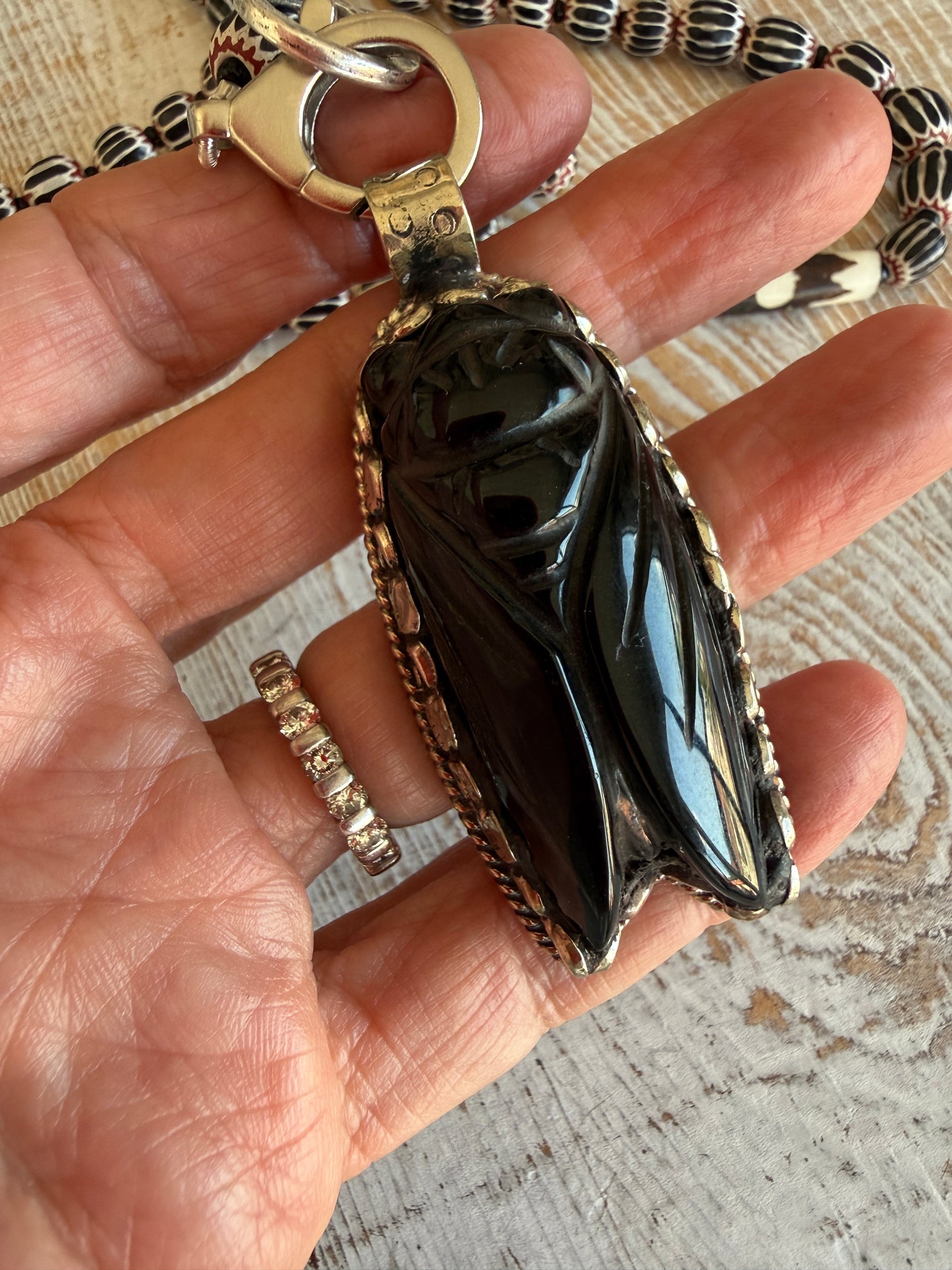 Obsidian beetle pendant on black, red, and white chevron beads with bone accent beads long necklace. Front lobster clasp. 34”