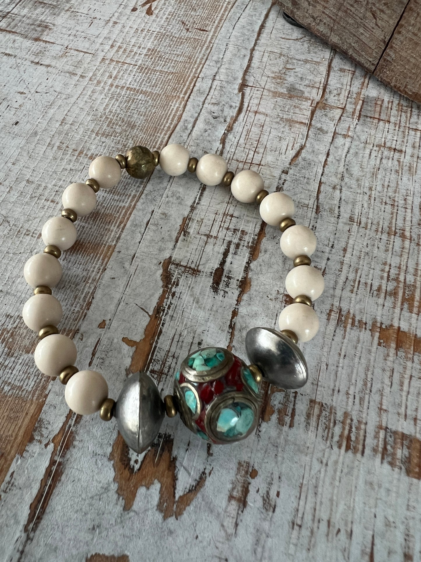 Tibetan inlay bead with coral and turquoise on matte riverstone beads. Stack stretch bracelet.