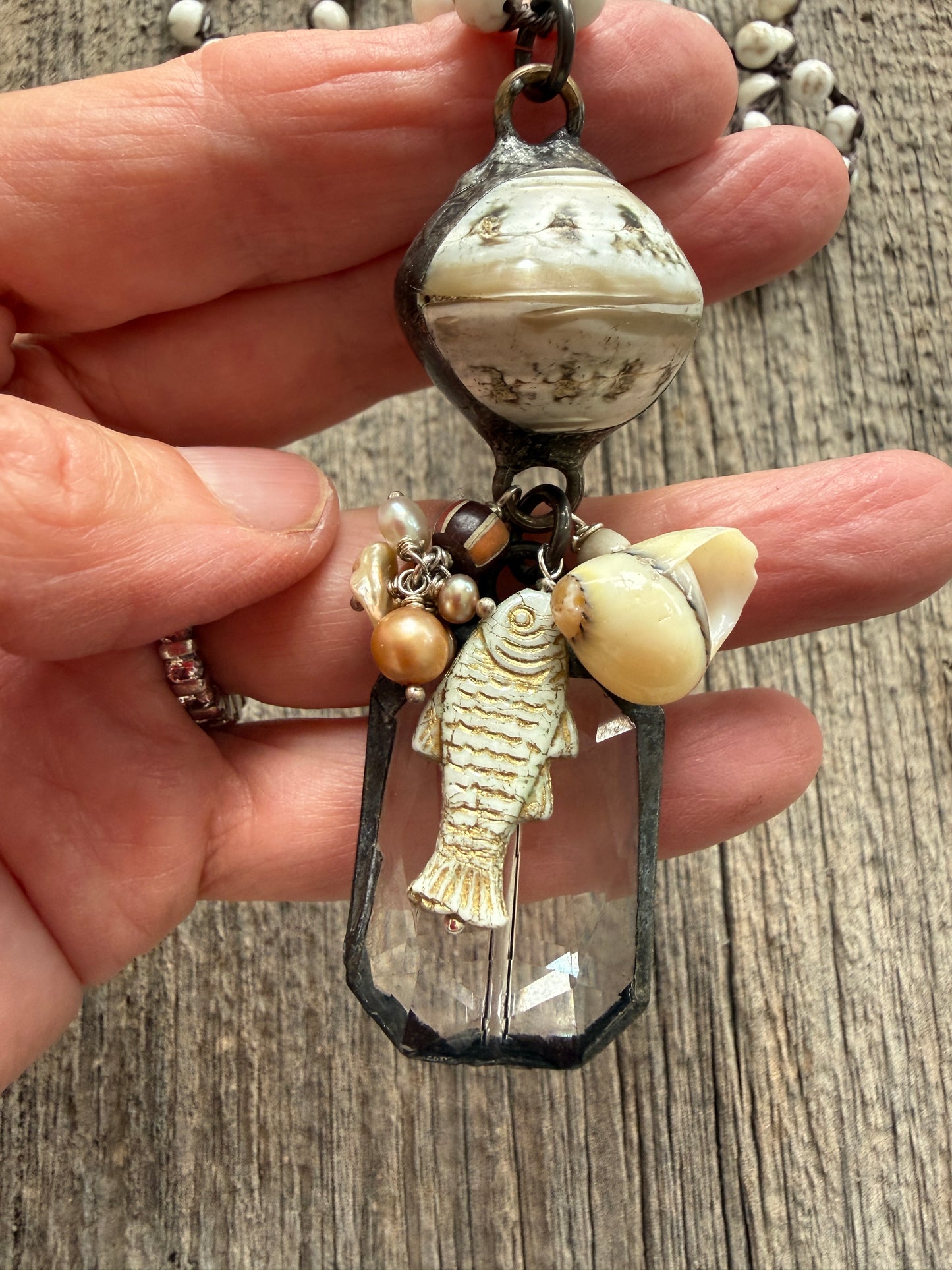 Long braided white magnesite with soldered shell and crystal pendant with pearls, trade bead, shell, and fish charm.