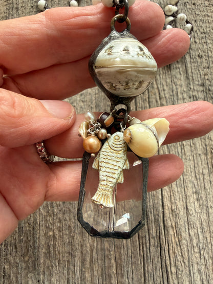 Long braided white magnesite with soldered shell and crystal pendant with pearls, trade bead, shell, and fish charm.