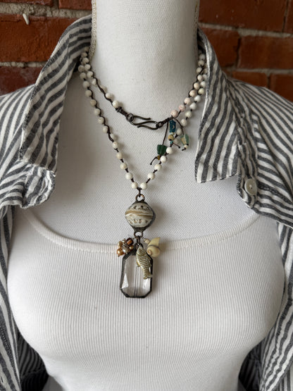 Long braided white magnesite with soldered shell and crystal pendant with pearls, trade bead, shell, and fish charm.