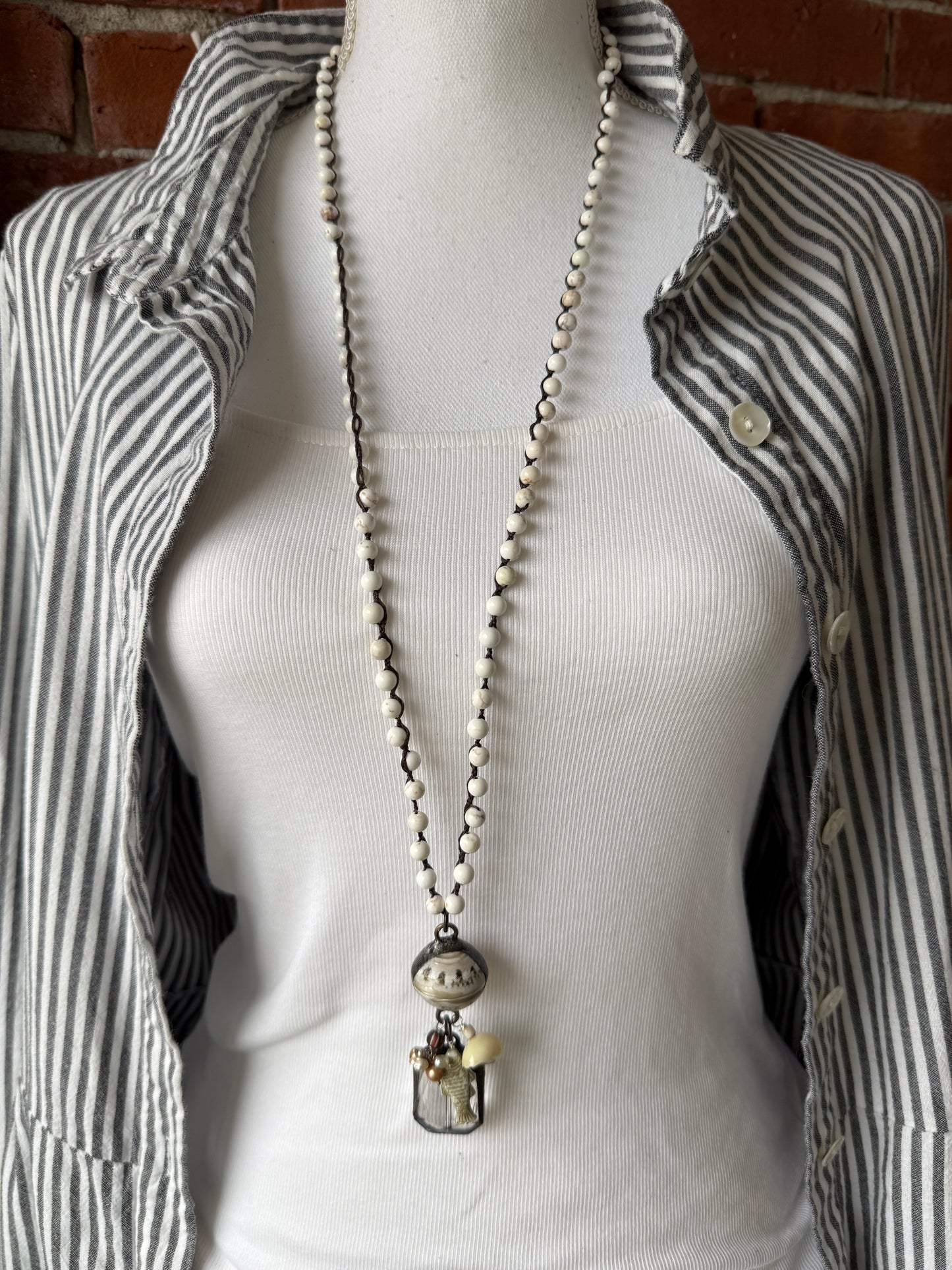 Long braided white magnesite with soldered shell and crystal pendant with pearls, trade bead, shell, and fish charm.