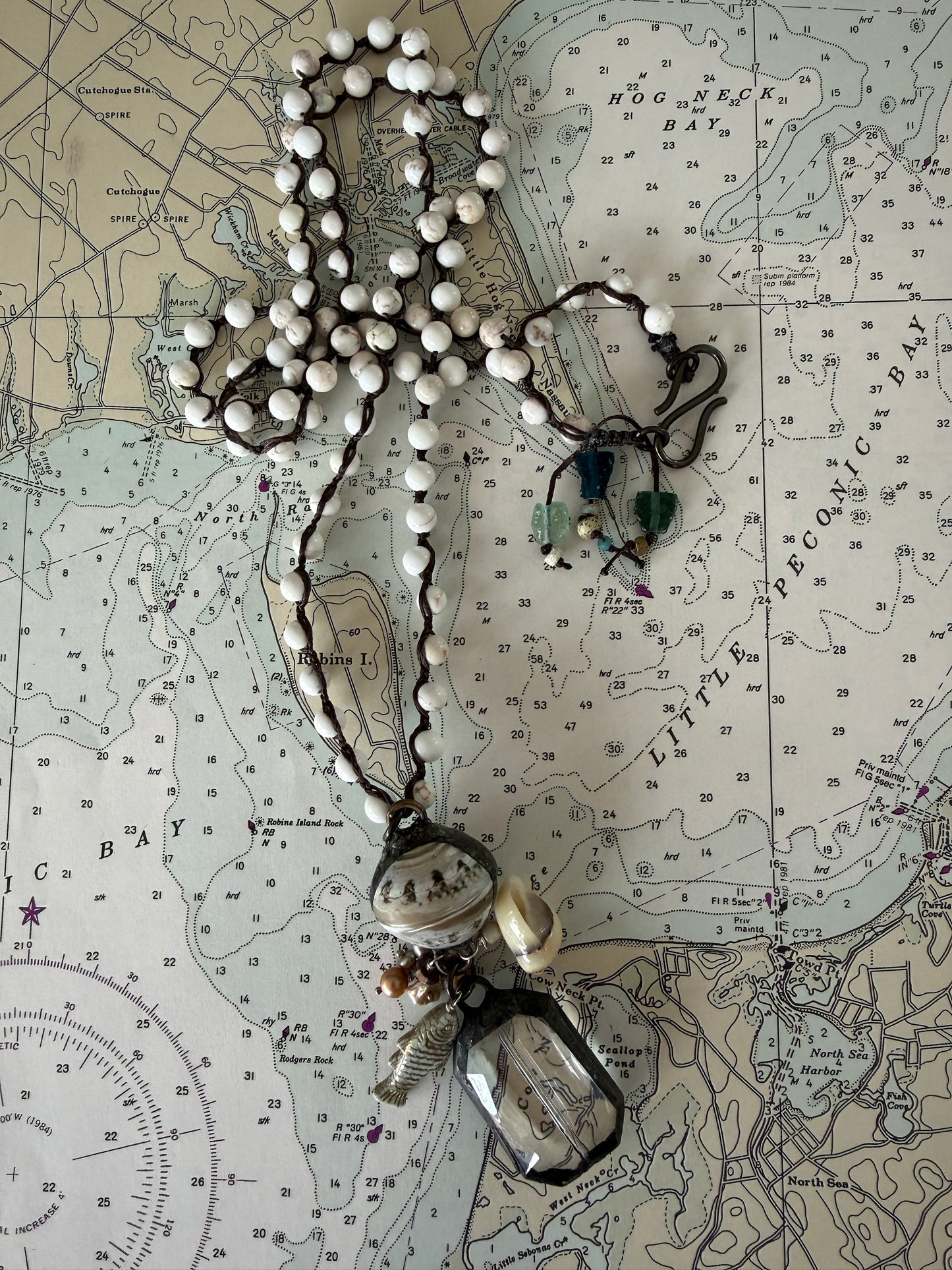 Long braided white magnesite with soldered shell and crystal pendant with pearls, trade bead, shell, and fish charm.