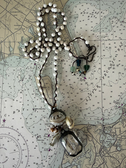 Long braided white magnesite with soldered shell and crystal pendant with pearls, trade bead, shell, and fish charm.