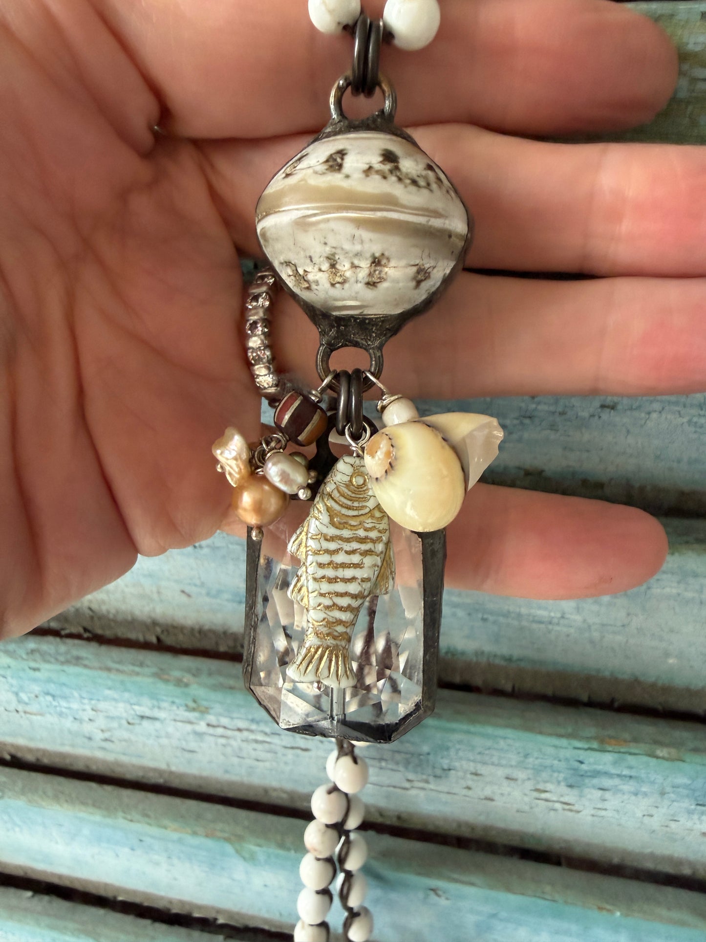 Long braided white magnesite with soldered shell and crystal pendant with pearls, trade bead, shell, and fish charm.
