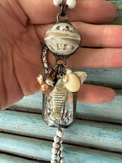 Long braided white magnesite with soldered shell and crystal pendant with pearls, trade bead, shell, and fish charm.