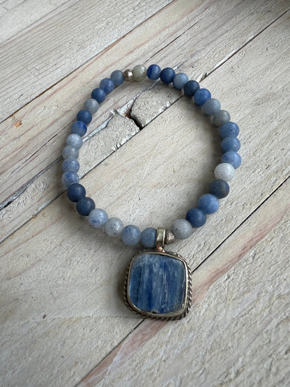 Tibetan blue kyanite pendant suspended from matte blue aventurine stack stretch bracelet. 7”