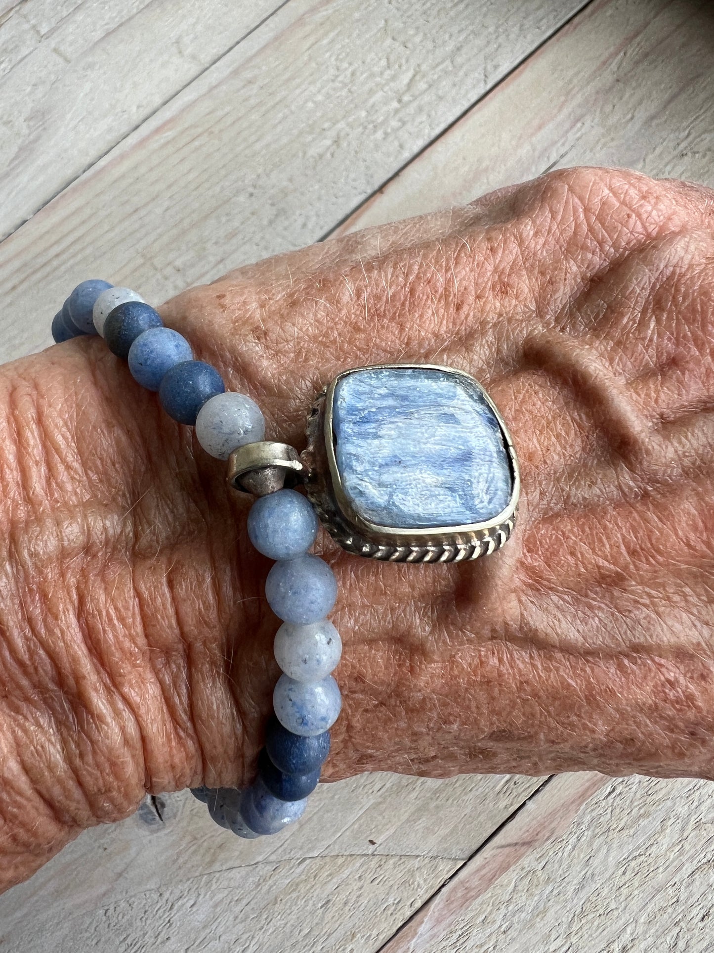 Tibetan blue kyanite pendant suspended from matte blue aventurine stack stretch bracelet. 7”