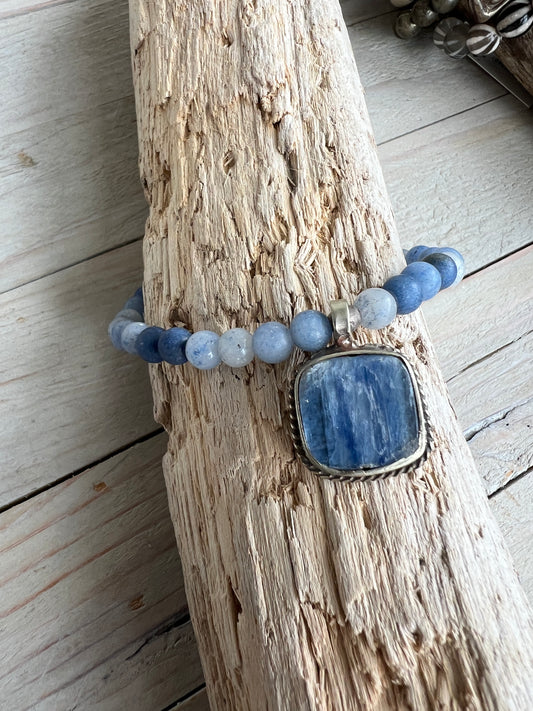 Tibetan blue kyanite pendant suspended from matte blue aventurine stack stretch bracelet. 7”