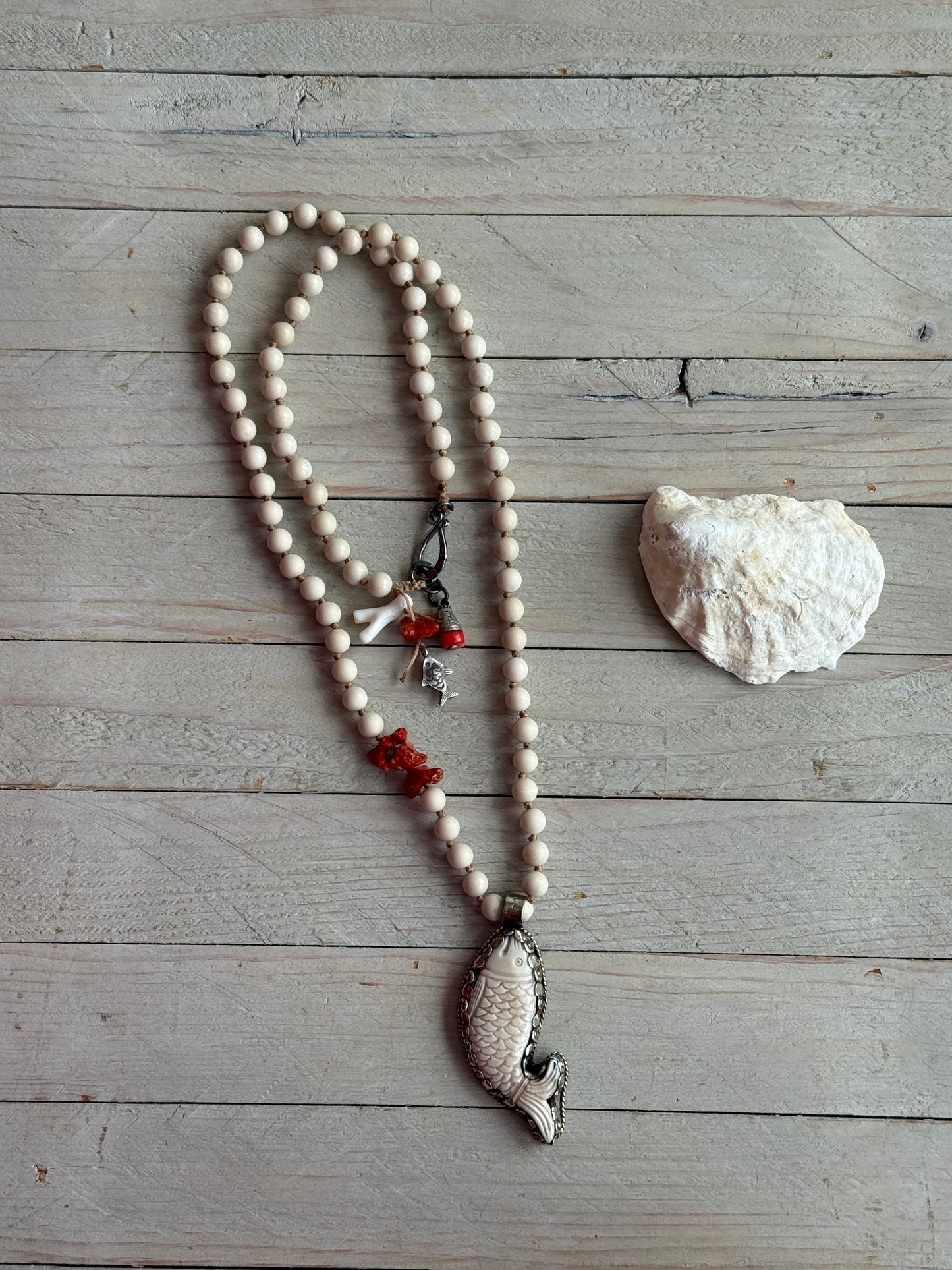 Tibetan carved bone fish on knotted riverstone and coral long necklace. Coral and fine silver fish charms.
