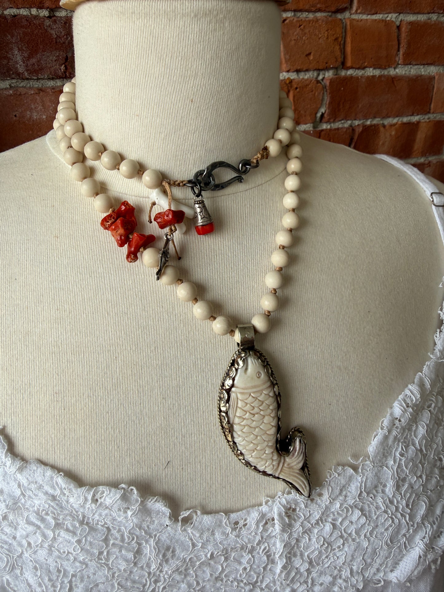 Tibetan carved bone fish on knotted riverstone and coral long necklace. Coral and fine silver fish charms.