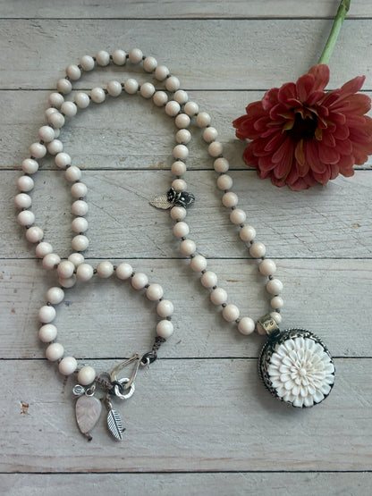 Tibetan carved bone dahlia pendant on hand knotted riverstone beads necklace. Fine silver flower cluster and MOP leaf dangles.